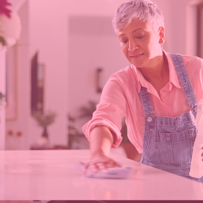 Pessoa a limpar superfície branca com pulverizador e pano
