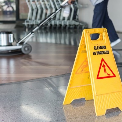 Sinal amarelo de aviso de limpeza em progresso num chão de azulejos cinzentos