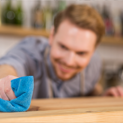 Homem a limpar balcão de madeira com pano azul
