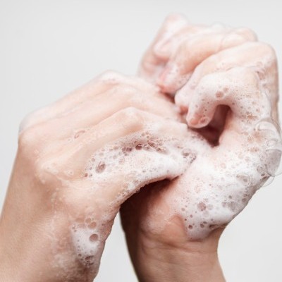 Mãos femininas a lavar-se com espuma branca
