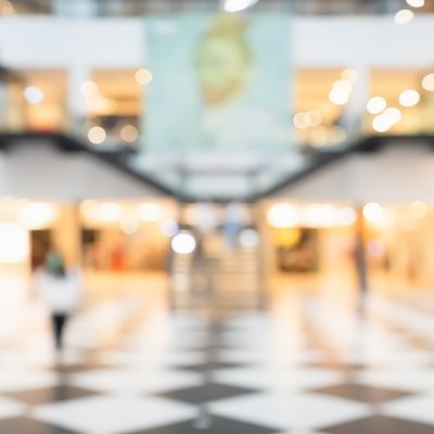 Interior desfocado de um centro comercial com piso xadrez e pessoas indistintas