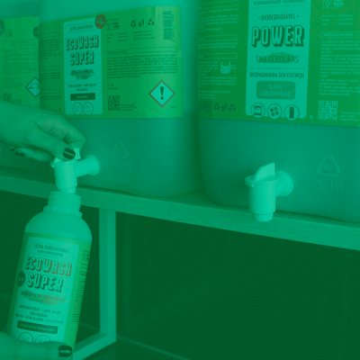Recipientes plásticos com torneiras e rótulos do detergente Ecowash Super numa prateleira.