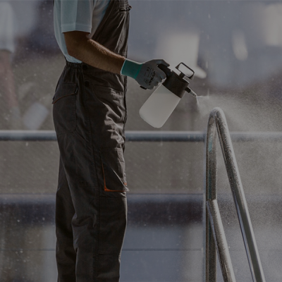 Homem a pulverizar estrutura metálica prateada com pulverizador branco e preto