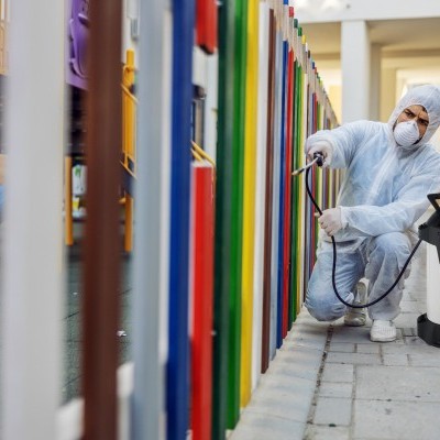 Pessoa em fatos de proteção a desinfetar grade colorida com pulverizador