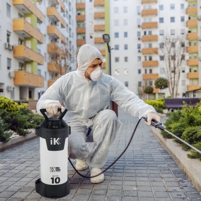 Pulverizador de pressão IK LUX 10L usado em ambiente urbano por pessoa com equipamento de proteção.