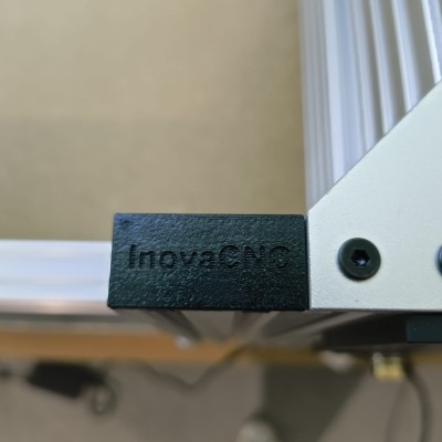 Estrutura metálica com peça preta de plástico e inscrição InovaCNC