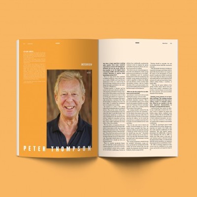 Revista aberta com página esquerda laranja claro e foto de homem e página direita com texto em colunas