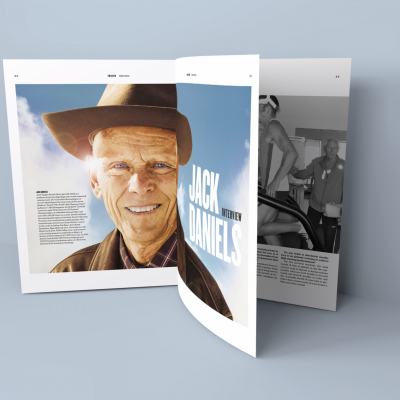 Revista aberta com foto a cores de homem com chapéu e texto JACK DANIELS e página em preto e branco com pessoas num ginásio