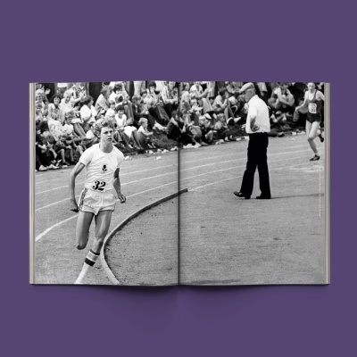Livro aberto com fotografia em preto e branco de corrida atlética com atleta número 32 e público nas bancadas.