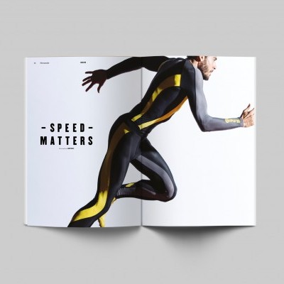 Homem correndo com roupa esportiva preta, amarela e cinza, texto INTERRUPTED MATTERS ao fundo em catálogo aberto