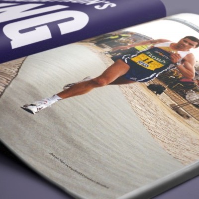 Revista aberta com fotografia de corredor a correr numa rua pavimentada