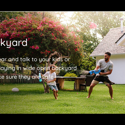 Adulto e criança a brincar com bola de água em jardim verde com casa branca ao fundo