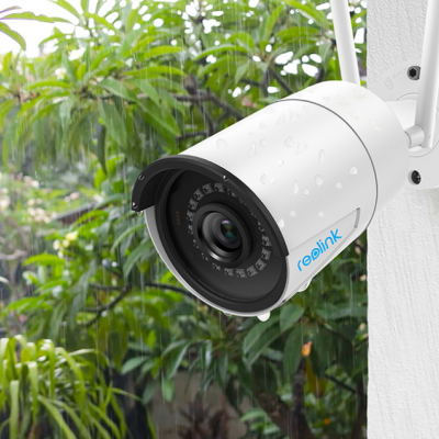 Câmera de vigilância branca reolink montada numa parede, com gotas de água e vegetação ao fundo