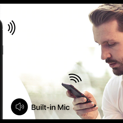 Homem a falar num dispositivo preto ao lado de um telemóvel com aplicação aberta e indicação de microfone embutido