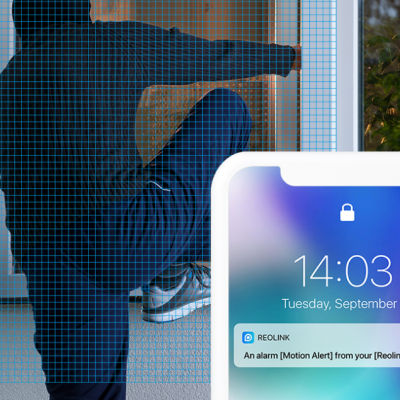 Pessoa tenta forçar porta de vidro com notificação de alerta de movimento no telemóvel.