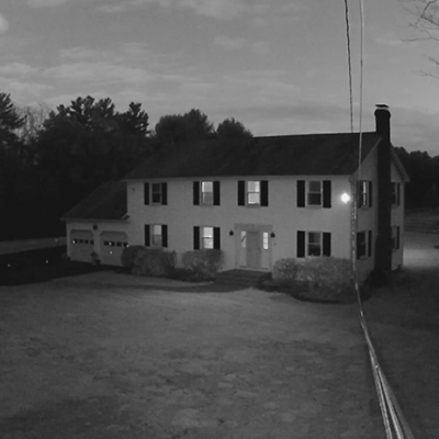 Casa grande de dois andares com relvado e árvores à volta vista à noite