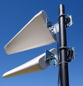 Duas antenas de painel cinza claras montadas em suporte preto sob céu azul