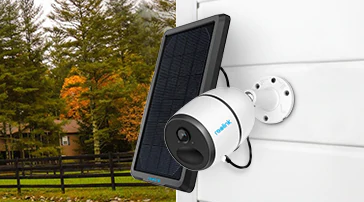 Câmara de vigilância branca com painel solar numa parede exterior