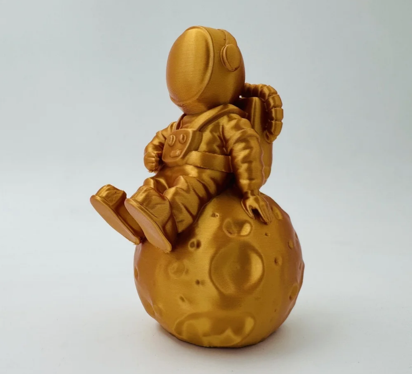 PLA SILK Deep Gold - Diâmetro 1,75mm Bobine 1kg - Lotactree Escultura dourada de astronauta sentado numa esfera com crateras