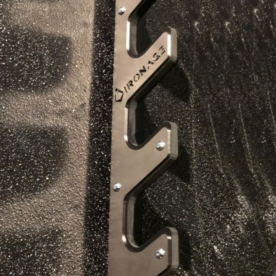 Estrutura metálica preta com palavra IRONAGE sobre superfície preta texturada