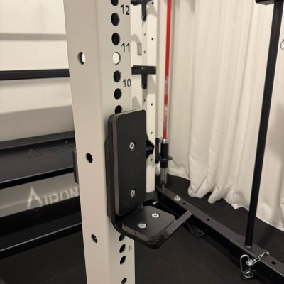 Suporte ajustável preto em estrutura branca perfurada com números num ginásio