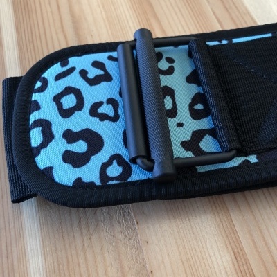 Cinta regulável azul com padrão de manchas pretas sobre mesa de madeira clara