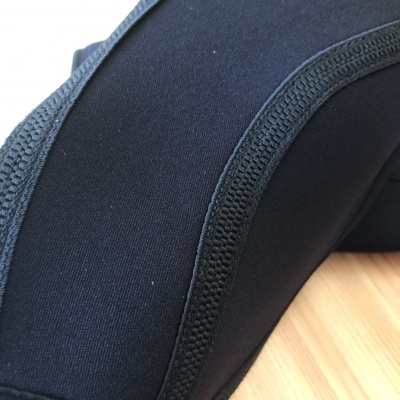 Joelheira preta elástica com costuras reforçadas sobre madeira clara