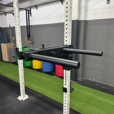 Estrutura metálica para exercícios com acessórios pretos e pesos coloridos num ginásio