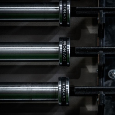 Barras de ferro com pegadas pretas e texto IRONAGE num suporte metálico.