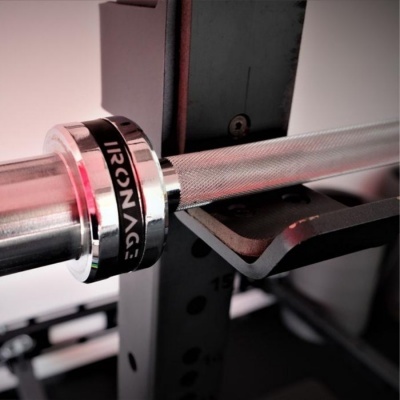 Barra de halteres metálica com anilha preta e prateada com texto IRONAG