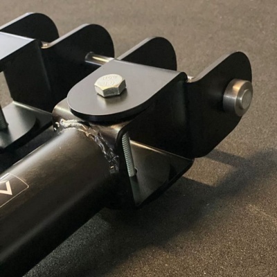 Componente metálico preto com parafuso hexagonal e porca, sobre superfície cinza.