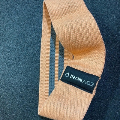 Faixa elástica amarela clara com etiqueta IRONAGE sobre superfície preta granulada
