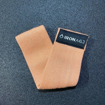 Elástico tecido bege com etiqueta IRONAGE sobre fundo preto