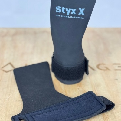 Suportes Styx X pretos em neoprene com velcro sobre superfície de madeira clara