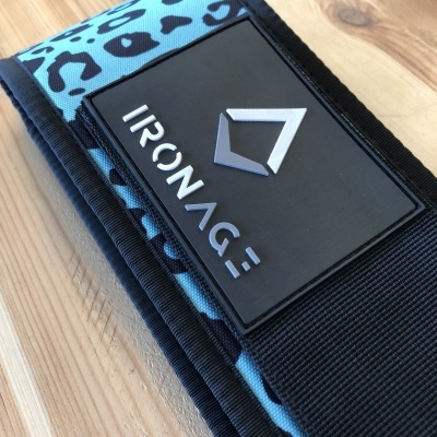 Cinta fitness azul com padrão de onça e etiqueta IRONAGE numa mesa de madeira