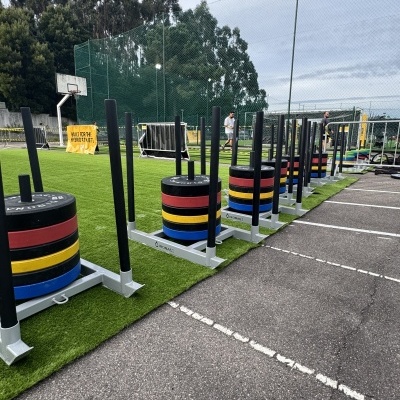 Pesos coloridos organizados em pegas metálicas em campo de treino ao ar livre