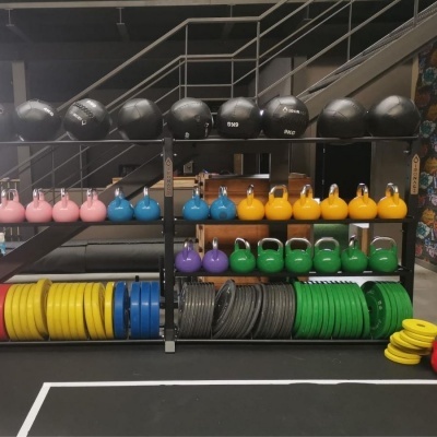 Variados equipamentos de ginásio coloridos organizados numa prateleira metálica