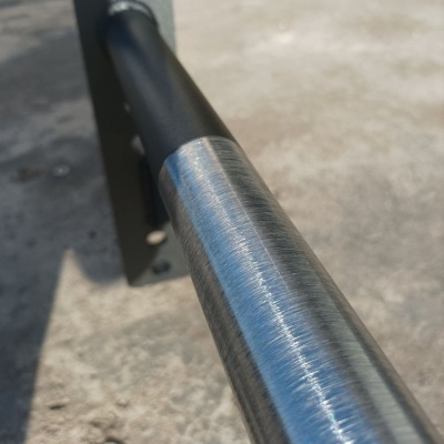 Barra metálica cilíndrica com suporte preto e chão cinzento