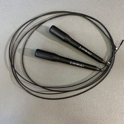 Corda de saltar preta com cabos finos e punhos pretos da marca IRONMAG3 sobre superfície cinzenta