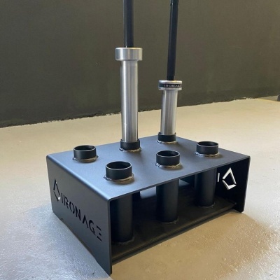 Estrutura metálica preta com tubos verticais para pesos, com duas colunas metálicas e texto IRON AGE