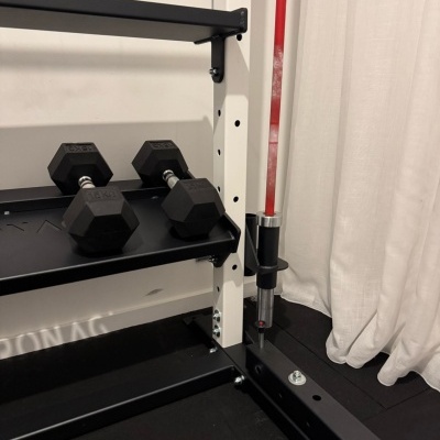 Suporte de halteres com halteres hexagonais e barra vermelha ao lado de cortina branca