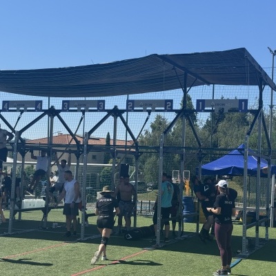 Campo de futebol com rede e cobertura, jogadores e espectadores em roupa desportiva