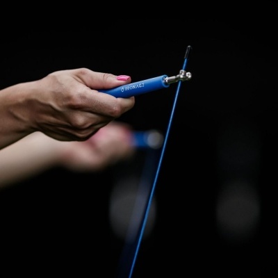 Mão segurando cabo azul com texto e dispositivo metálico, fundo escuro