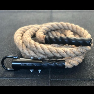 Corda de treino grossa bege com extremidades pretas e fixações metálicas sobre piso preto