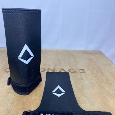 Munhequeiras pretas com logótipo e etiqueta IRON AGE sobre superfície de madeira