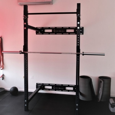 Estrutura de halterofilismo preta com barra cromada e acessórios de ginásio