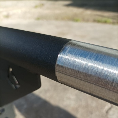 Suporte metálico com tubo preto e secção em aço escovado em fundo claro desfocado