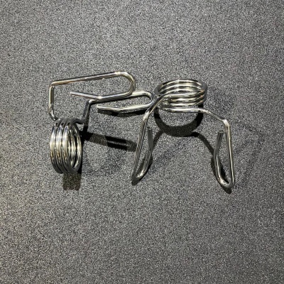 Três ganchos metálicos prateados com molas sobre superfície preta