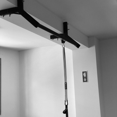 Barra de puxar de exercício preta com alça suspensa em parede branca interior