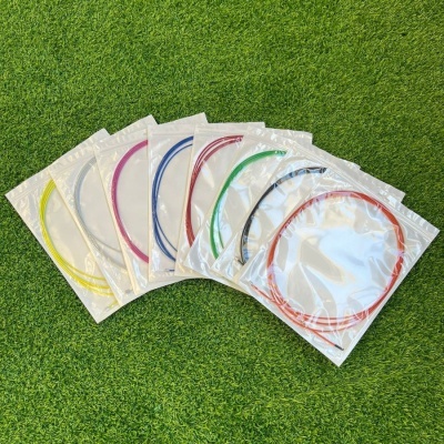 Cabos coloridos para guitarra elétrica ou acústica embalados em plástico sobre relva.